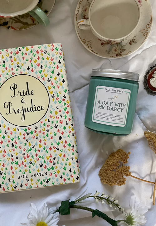Day With Mr. Darcy candle on white table linen with tea cups and Jane Austen's Pride and Prejudice book and faux flowers