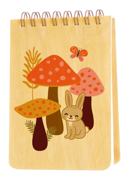 Notebook with mushroom and rabbit illustration on a wooden background