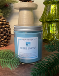Candle labeled 'Shire Snow' with decorative elements on a wooden surface
